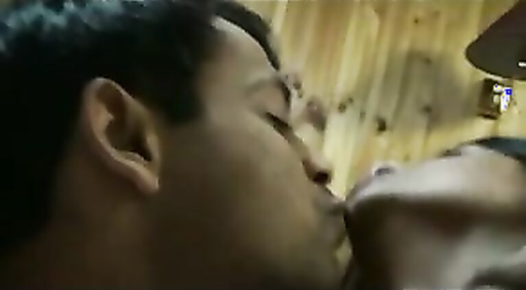 Indian couple on their honeymoon laying naked in bed enjoying passionate seductive french kissing.